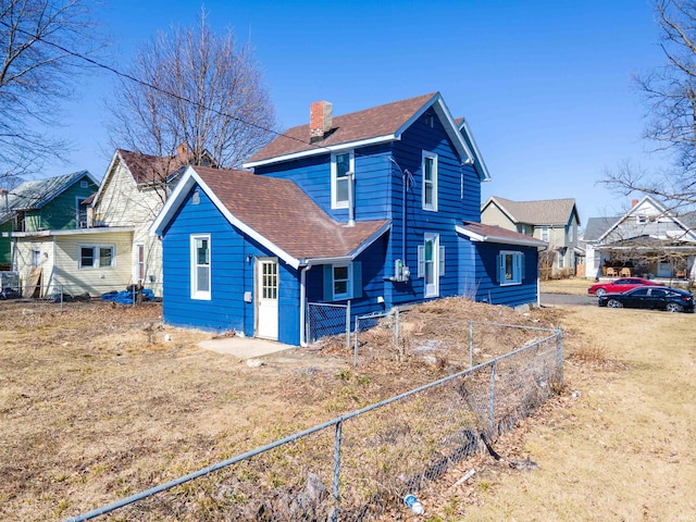 exterior space featuring fence, roof with shingles, and a chimney