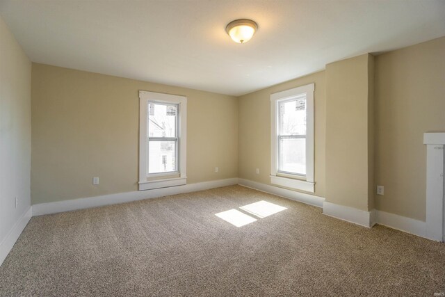 unfurnished room featuring a healthy amount of sunlight, light colored carpet, and baseboards