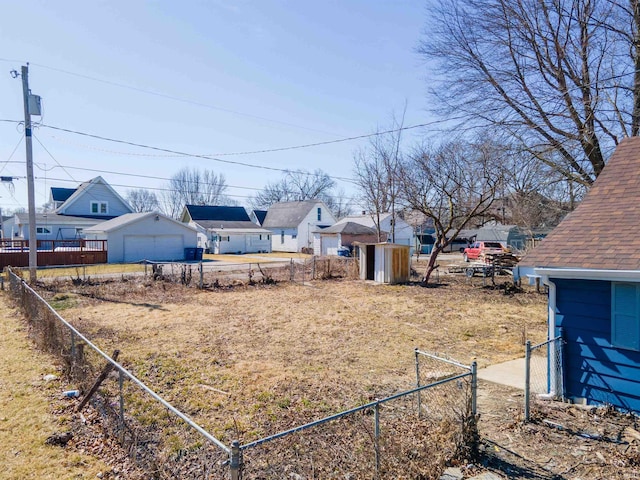 view of yard with an outbuilding, a residential view, a garage, and fence