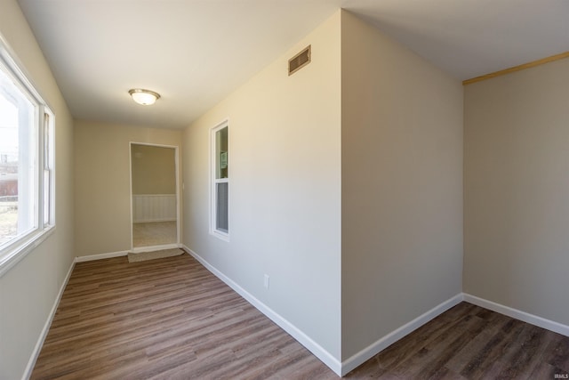 hall featuring visible vents, baseboards, and wood finished floors