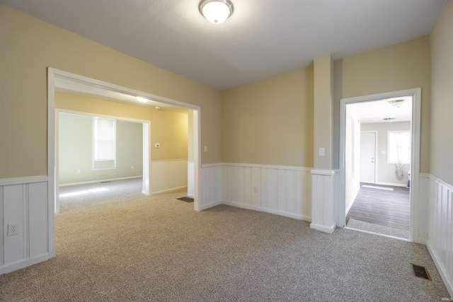 spare room featuring a wainscoted wall, carpet floors, and visible vents