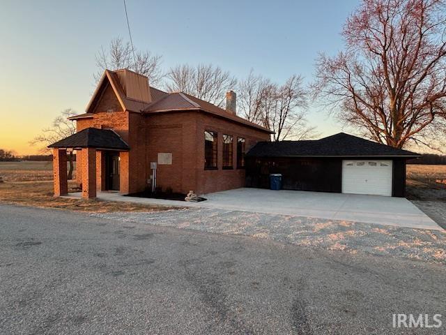 property exterior at dusk featuring a garage and a chimney