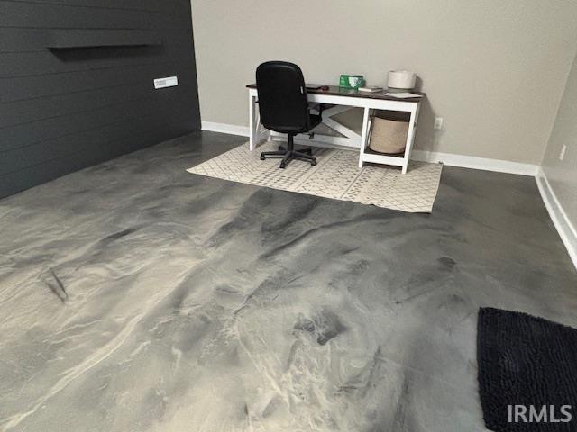 home office featuring baseboards and finished concrete flooring