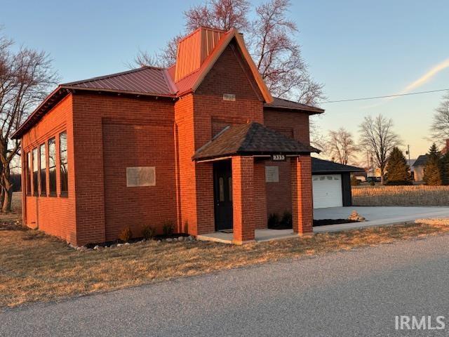 property exterior at dusk with brick siding and metal roof