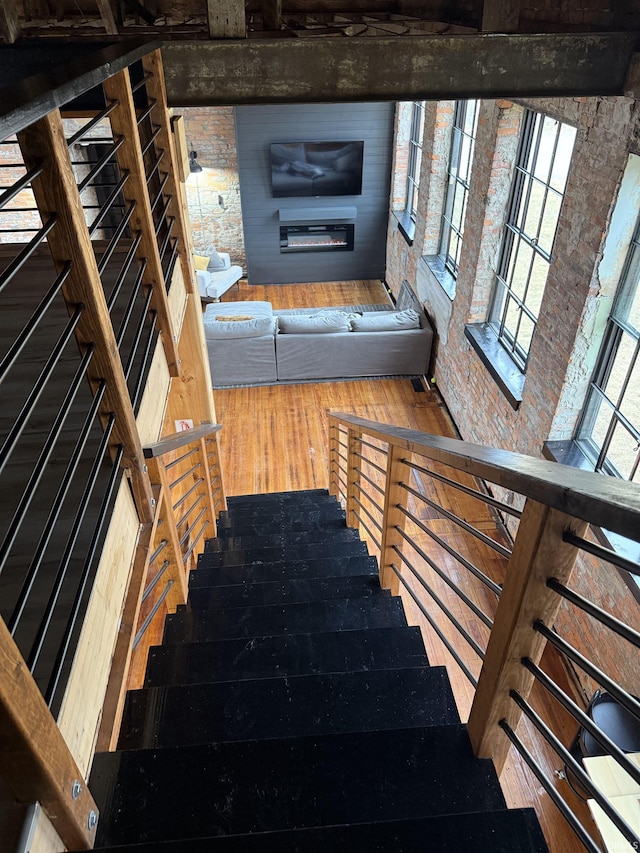 stairway featuring brick wall and wood finished floors