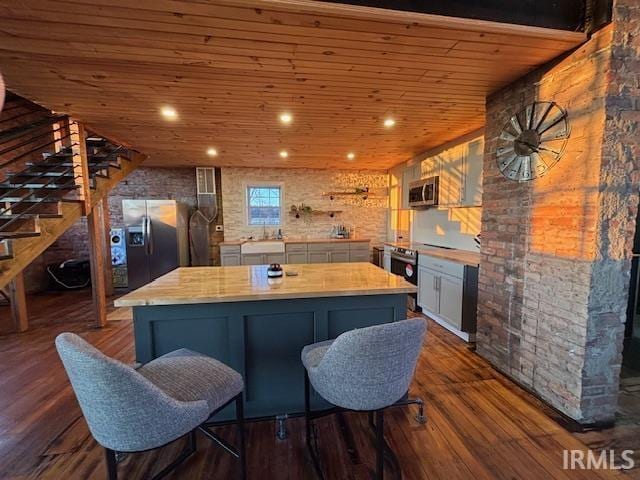 kitchen with dark wood-style floors, a kitchen island, a sink, stainless steel appliances, and wood ceiling