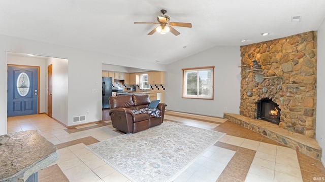 living room featuring light tile patterned floors, baseboards, visible vents, vaulted ceiling, and a fireplace