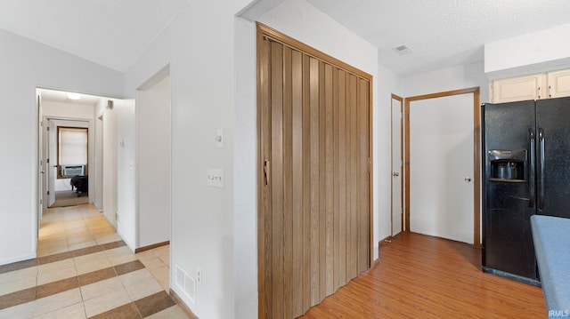 corridor featuring lofted ceiling, light tile patterned floors, a textured ceiling, and visible vents