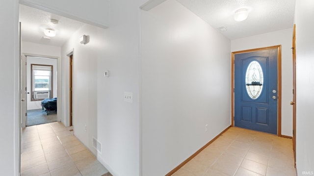 foyer entrance featuring visible vents, a textured ceiling, baseboards, and light tile patterned floors