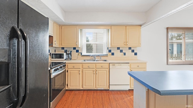 kitchen featuring white appliances, light wood-type flooring, a sink, and tasteful backsplash