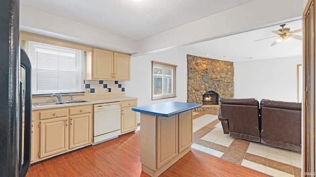 kitchen featuring cream cabinets, light wood-style floors, a sink, dishwasher, and black fridge