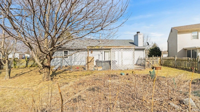 rear view of property featuring a yard, fence, and a chimney