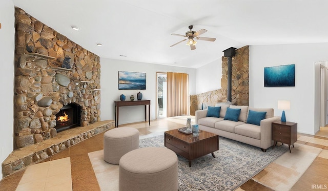 living area featuring lofted ceiling, a stone fireplace, tile patterned flooring, and a ceiling fan