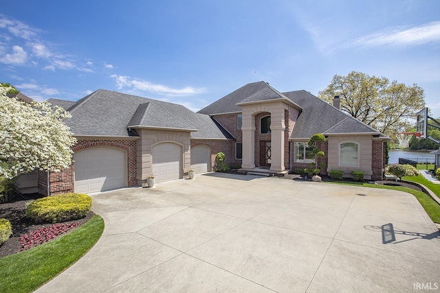 french provincial home featuring concrete driveway, brick siding, an attached garage, and roof with shingles