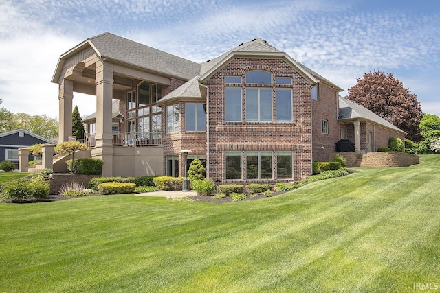 back of property with a lawn and brick siding