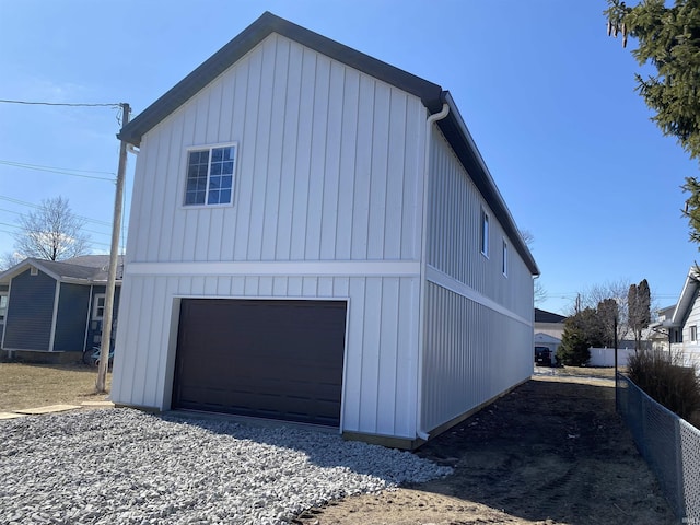 view of side of home with board and batten siding, fence, and an attached garage