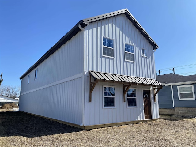 back of property featuring metal roof, a standing seam roof, and board and batten siding