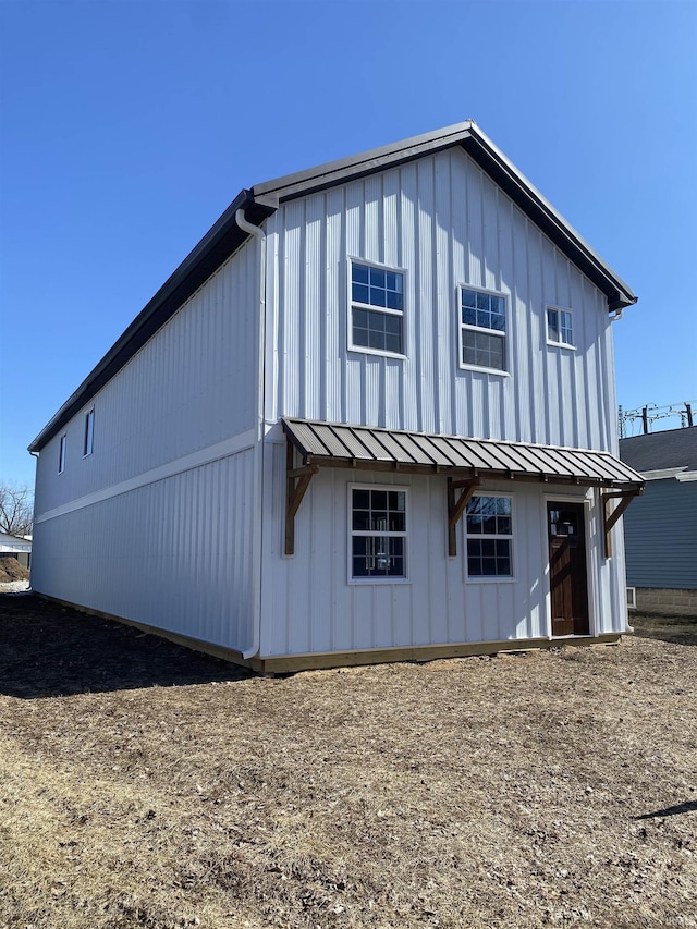 rear view of property with metal roof, a standing seam roof, and board and batten siding