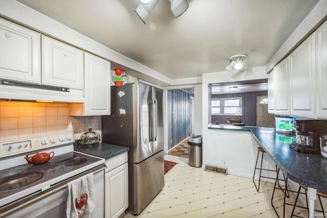 kitchen featuring under cabinet range hood, tasteful backsplash, white range with electric stovetop, and white cabinetry