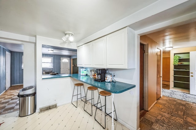 kitchen with dark countertops, a kitchen bar, visible vents, and white cabinets