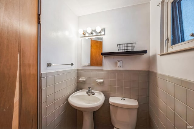 bathroom featuring toilet, tile walls, and wainscoting