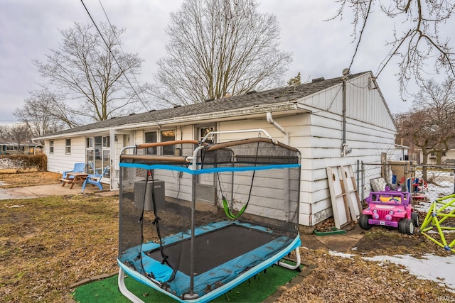 back of property with a patio, a trampoline, and fence