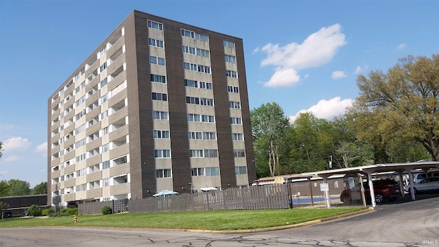 view of building exterior featuring covered parking and fence