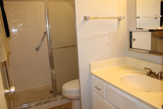 bathroom featuring toilet, a stall shower, and vanity