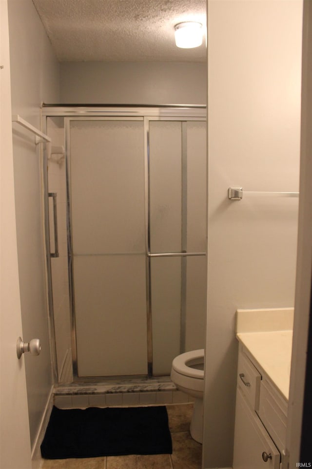 bathroom with a textured ceiling, vanity, a shower stall, and toilet