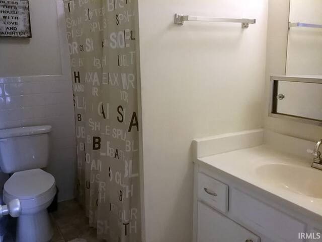 bathroom featuring a shower with shower curtain, vanity, toilet, and tile patterned floors