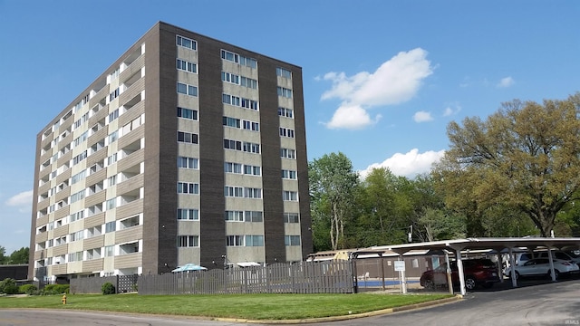 view of building exterior with covered parking and fence