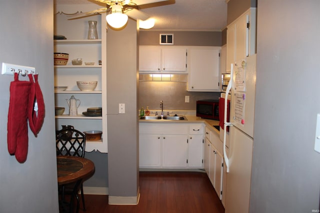 kitchen featuring visible vents, stainless steel microwave, white cabinets, and a sink