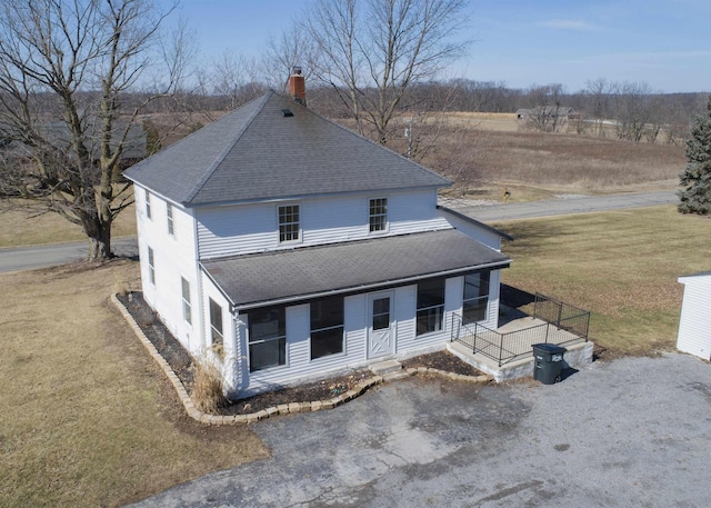 view of front facade featuring a porch, a shingled roof, a chimney, and a front lawn