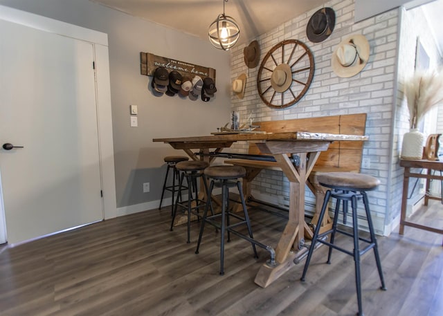 dining room with brick wall, baseboards, and wood finished floors