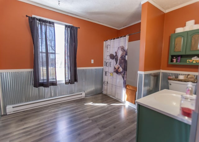 full bathroom featuring a wainscoted wall, wood finished floors, crown molding, a textured ceiling, and a baseboard heating unit