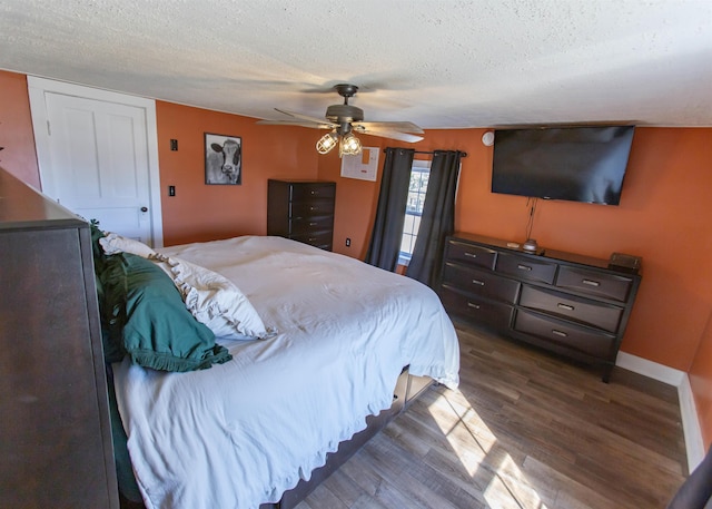 bedroom featuring a textured ceiling, dark wood-type flooring, a ceiling fan, and baseboards