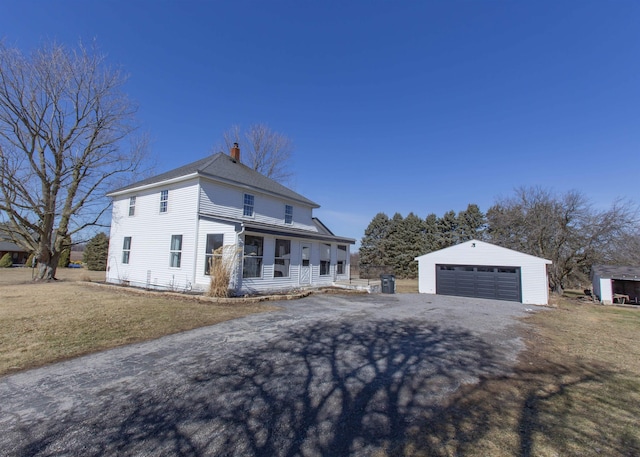 traditional style home with a garage, a chimney, roof with shingles, an outbuilding, and a front yard