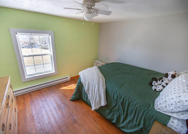 bedroom with hardwood / wood-style flooring, ceiling fan, baseboard heating, and a textured ceiling