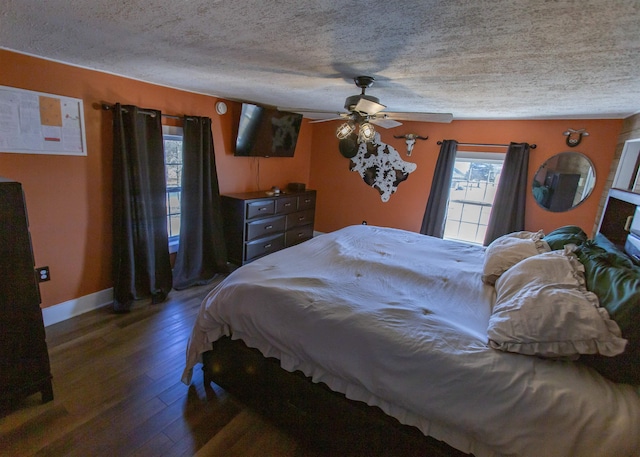 bedroom with ceiling fan, a textured ceiling, baseboards, and wood finished floors