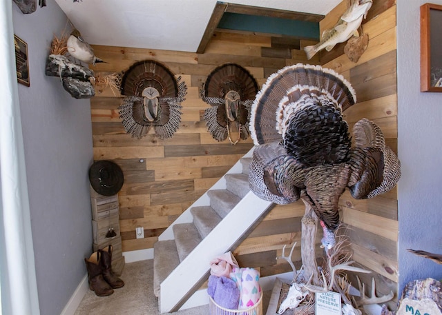 stairway featuring wood walls and carpet