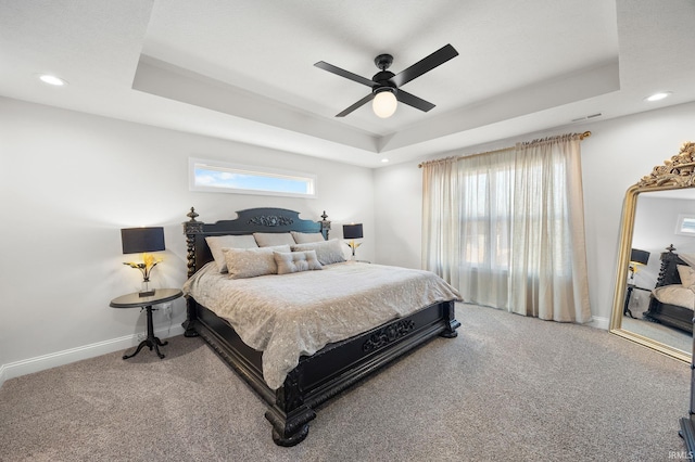 bedroom with carpet floors, baseboards, and a tray ceiling