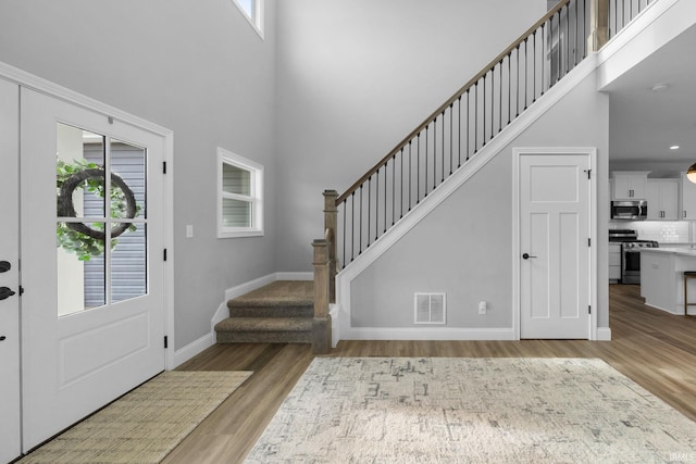 foyer entrance with stairs, wood finished floors, visible vents, and a healthy amount of sunlight