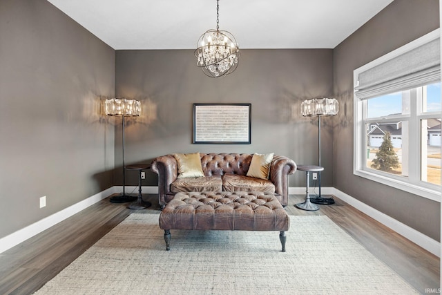 living area with an inviting chandelier, baseboards, and wood finished floors