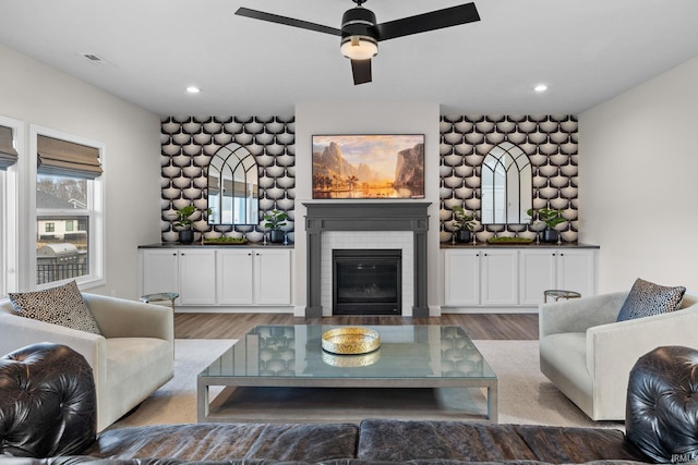 living area with recessed lighting, visible vents, a fireplace, and wood finished floors