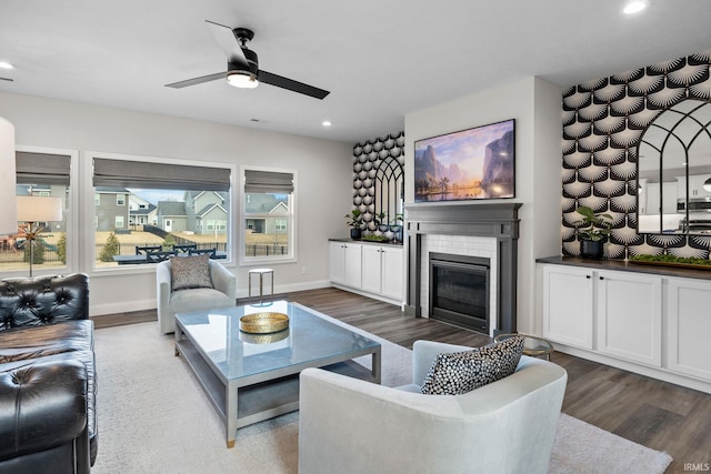 living area with recessed lighting, baseboards, wood finished floors, and a glass covered fireplace