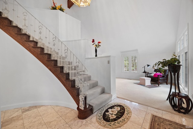 stairway with a high ceiling, tile patterned floors, carpet flooring, and baseboards