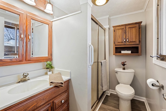 bathroom with toilet, ornamental molding, wood finished floors, vanity, and a shower stall