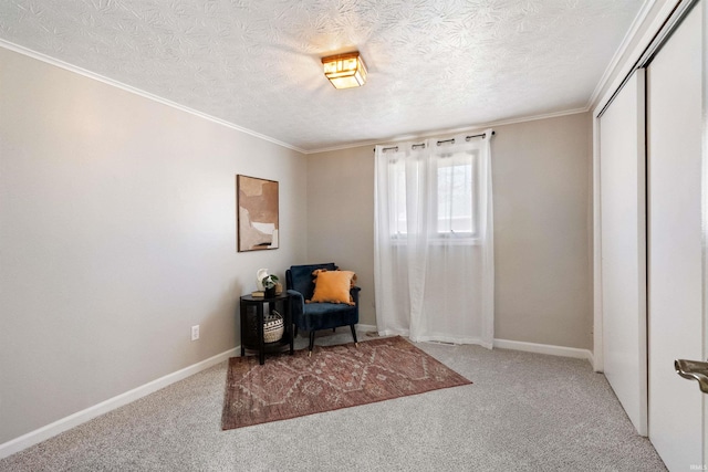 sitting room with a textured ceiling, carpet floors, crown molding, and baseboards