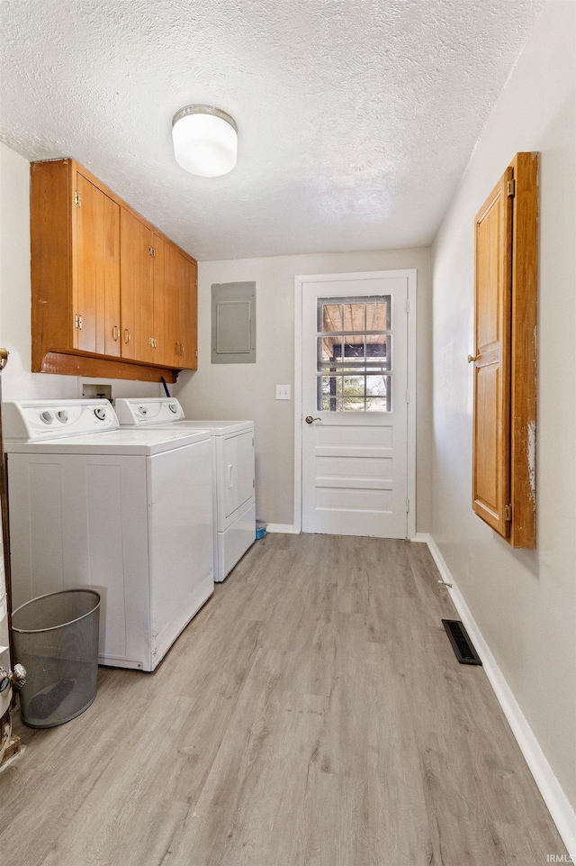 washroom featuring cabinet space, visible vents, a textured ceiling, light wood-type flooring, and independent washer and dryer