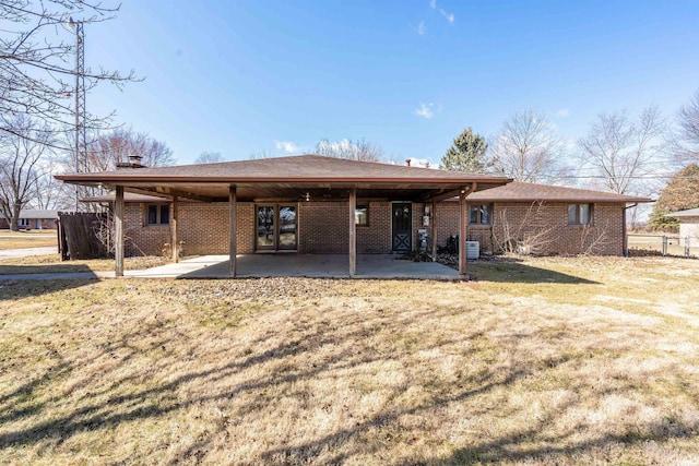 rear view of property featuring a patio area, brick siding, fence, and a lawn